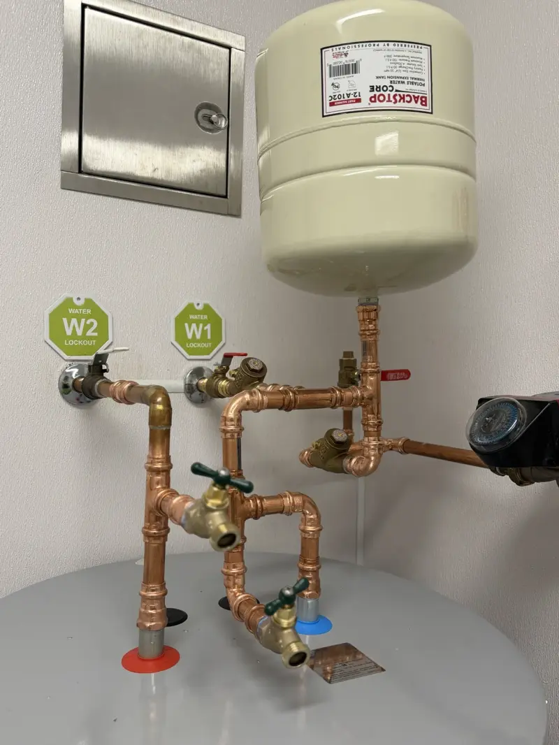 Clean copper water heater installation with expansion tank and recirculation pump by Hot Water Heater Factory